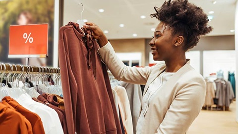 vrouw staat in winkel waar solden zijn en bekijkt een trui